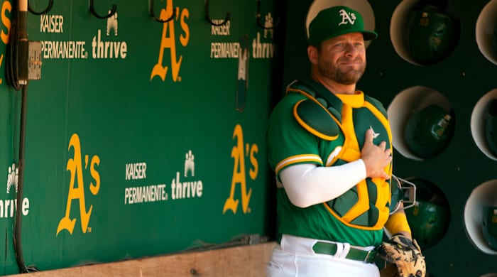 Stephen Vogt stands in the dugout wearing catchers’ gear with one hand over his heart